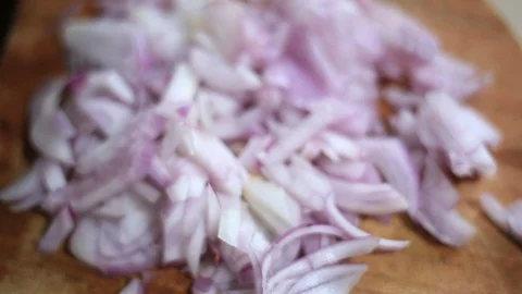 Blurry shallow focus close view of small onion pieces or slices on wood. Video stock 129480473