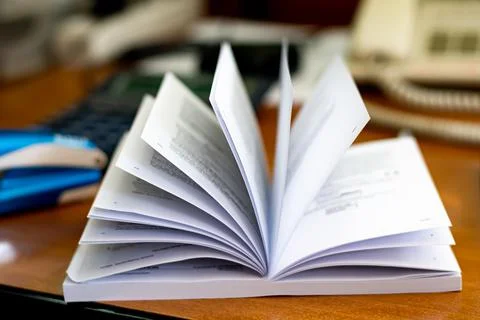 Blurry sheets of opened book atop office table Stock Photos