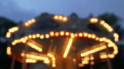Blurry shot of a rotating carousel with glowing lights at the evening. Vidéo 277225506