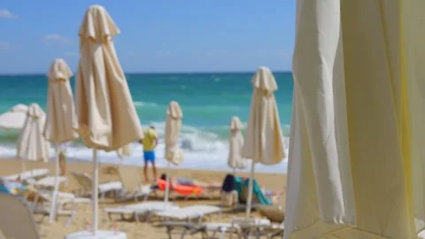 Blurry view of beach umbrellas and sunbathers on a sunny coast in 4k slow m.. Stock Footage 284309944