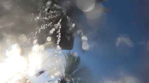Blurry water drops creating a dynamic splash effect with a palm tree, sun, and Stock Footage 339821773