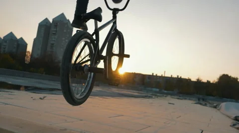 A bmx athlete does a trick in a sunset scenery in slow motion Stock Footage 57346384