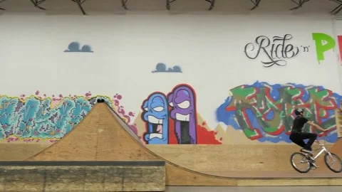 BMX rider does 360 bar spin, front wheel stall, and 180 bar spin at skate park. Stock Footage 72904774