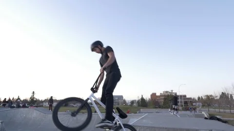 A bmx rider does bar spin trick in air at skate park Stock Footage 119983617