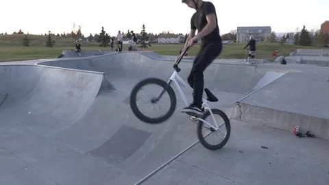 A bmx rider does bar spin trick in air at skate park Stock Footage 119983645