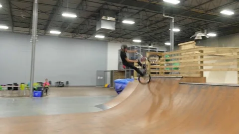 BMX rider does no hander and tail whip at skate park Stock Footage 72904761