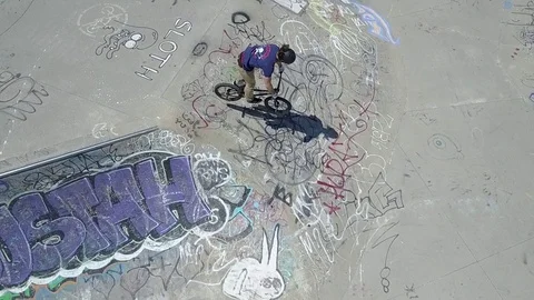 BMX rider doing a 360 bar spin on a graffiti covered jump Stock Footage 76098555
