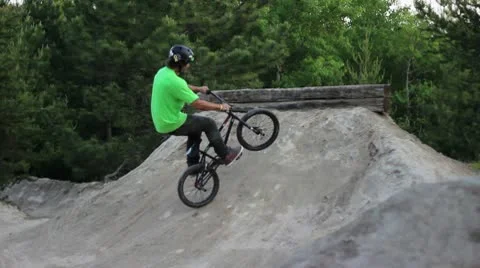 Bmx rider doing a downside tailwhip on a dirt obstacle Stock Footage 8960191