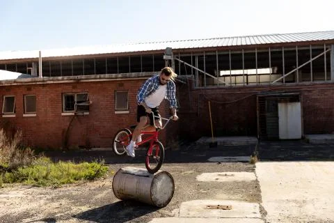 BMX rider doing trick in an empty yard Stock Photos