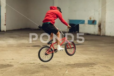 BMX rider in an empty warehouse jumping Stock Photos