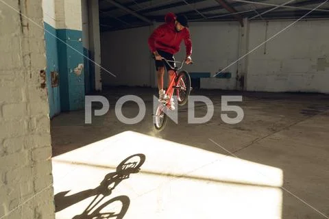 BMX rider in an empty warehouse jumping Stock Photos