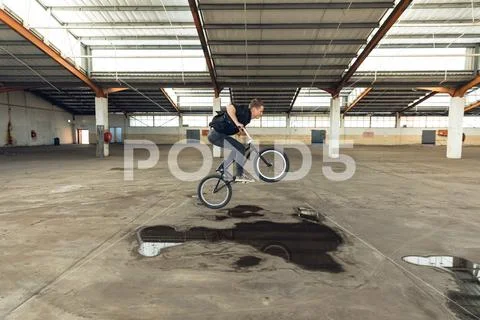 BMX rider in an empty warehouse jumping Stock Photos