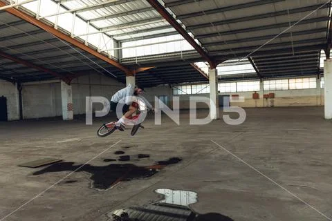 BMX rider in an empty warehouse jumping Stock Photos