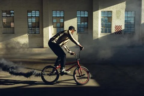 BMX rider in an empty warehouse using smoke grenade Stockfoto's