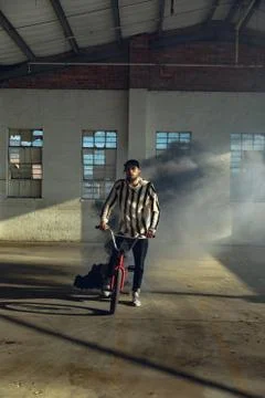 BMX rider in an empty warehouse using smoke grenade Stock Photos