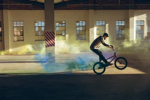 BMX rider in an empty warehouse using smoke grenade Stock Photos