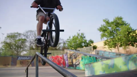 BMX rider enters frame in focus and rides along rail at skatepark slow motion Stock Footage 337220468