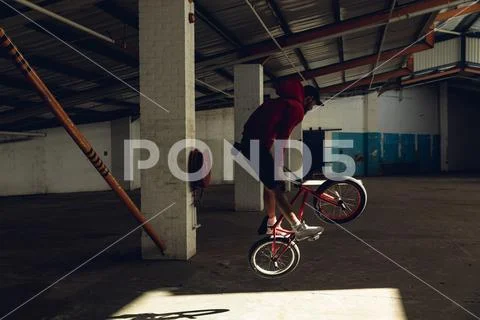 BMX rider jumping in an empty warehouse Stock Photos