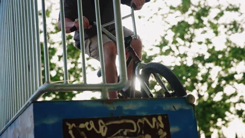BMX rider jumping from platform with sun flare in skatepark slow motion Stock Footage 336936654