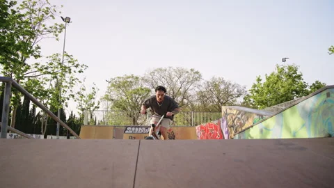 BMX rider jumping with spin towards camera in skatepark slow motion tracking Stock Footage 336937107
