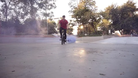 Bmx rider practicing in the empty skate park, riding on the bike while blue Видео 119072101