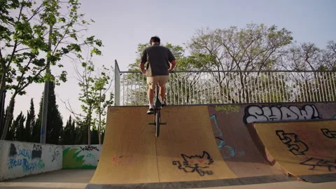 BMX rider riding up and down ramp from behind in skatepark slow motion Stock Footage 336936672