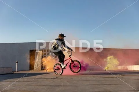 BMX rider on a rooftop using smoke grenades Stock Photos