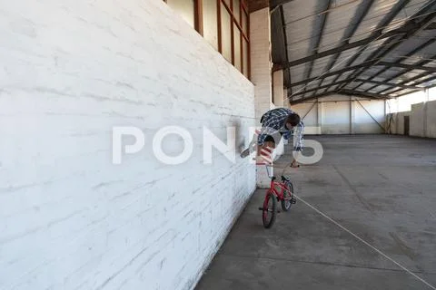 BMX rider running on wall in an empty warehouse Stock Photos