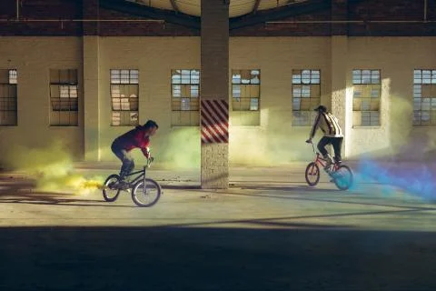 BMX riders in an empty warehouse using smoke grenades Stock Photos
