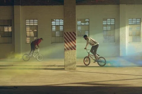 BMX riders in an empty warehouse using smoke grenades Stock Photos