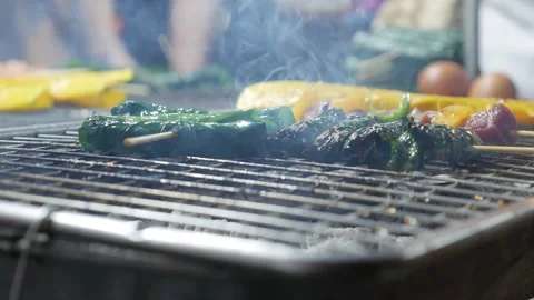 Bo la lot, or beef wrapped in betel leaves, roasts over glowing coals, its rich 스톡 동영상 307378537