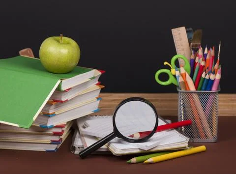 Board, books, pencils, opened empty notebook against a dark background. Stock Photos