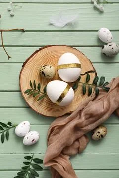 Board with Easter eggs and leaves on green wooden background Stock Photos