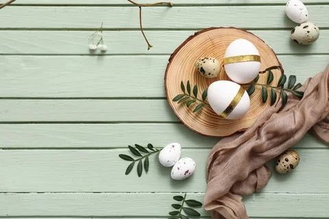 Board with Easter eggs and leaves on green wooden background Stock Photos
