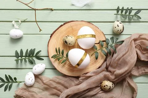Board with Easter eggs and leaves on green wooden background Stock Photos