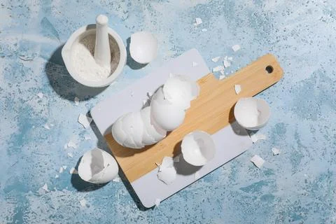 Board with egg shells and mortar on blue grunge background Foto stock