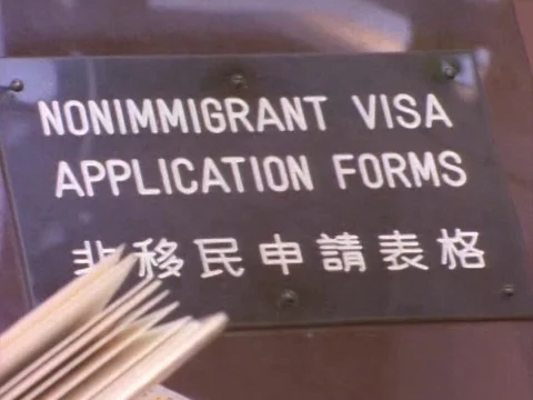 Board mentioning 'nonimmigrant visa application forms' and people filling them Stock Footage 79878274