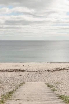 Board path to an empty beach and a calm sea. Stock Photos