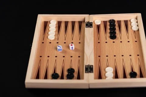 Board for playing backgammon with pieces and dice on a black background. 写真素材