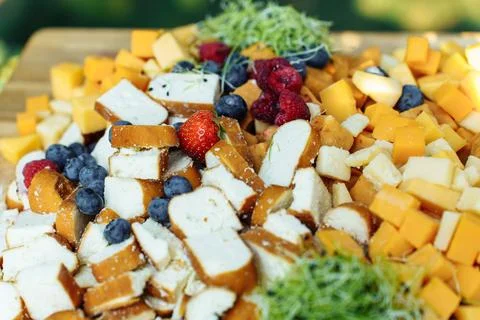 Board with sliced cheese, bread and berries for a festive buffet in the summer Stock Photos