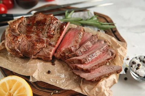 Board with tasty grilled steak on table Stock Photos