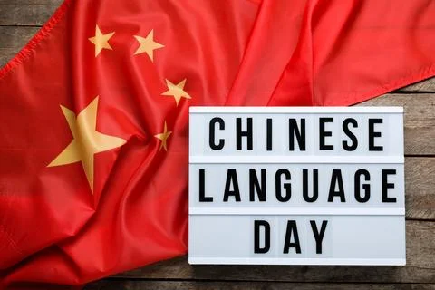 Board with text CHINESE LANGUAGE DAY and flag on wooden background Stock Photos