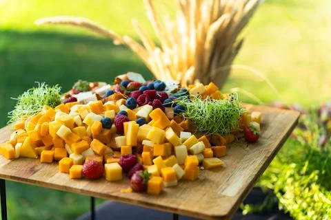 Board with various types of cheese and fruits prepared for a buffet in the .. Stock Photos