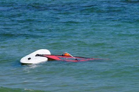 A board with a windsurf sail float in the sea without people Stock Photos