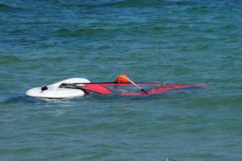 A board with a windsurf sail float in the sea without people Stock Photos