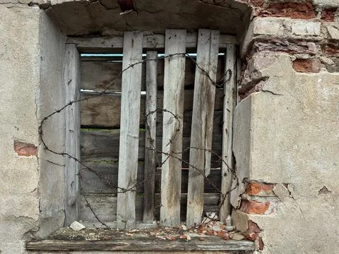 Boarded up Old Window with Barbed Wire on Weathered Wall 库存照片