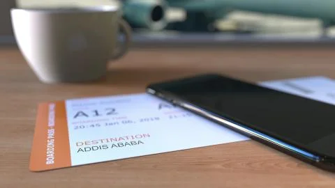 Boarding pass to Addis Ababa and smartphone on the table in airport while Stock Illustration