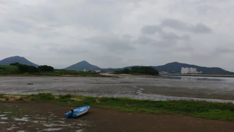 A boat alone on a mudflat overlooking the city across the sea_no sound Stock Footage 137160924