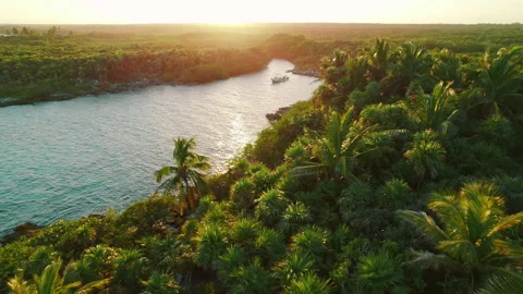 Boat anchored in tropical lagoon surrounded by dense jungle at golden sunset Stock Footage 336483901