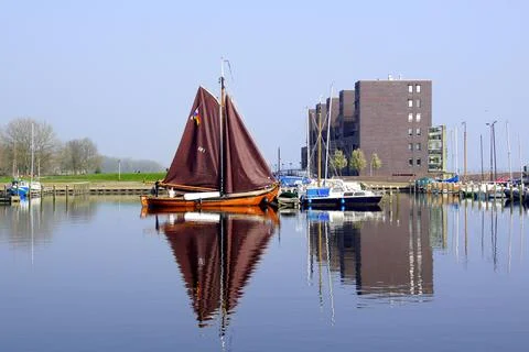 Boat and building reflecting in the water of the harbor of Almere Haven. Stock Photos